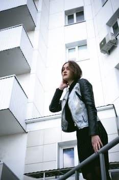 street portrait of a girl student, fashionably dressed in dark clothes, with a black backpack and denim jacket autumn sunny day