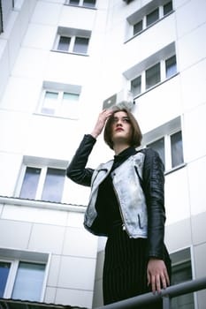 street portrait of a girl student, fashionably dressed in dark clothes, with a black backpack and denim jacket autumn sunny day