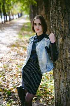 street portrait of a girl student, fashionably dressed in dark clothes, with a black backpack and denim jacket autumn sunny day