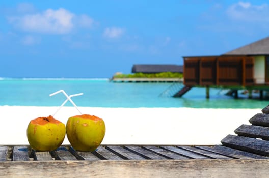 Tropical fresh coconut cocktail on white beach. Two coconut drinks on luxury tropical resort in Maldives island beach with  sea background.