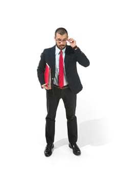 Full body or full-length portrait of businessman with red folder on white studio background. Serious bearded young man in glasses, suit, red tie standing in office. Business, career, success concept.