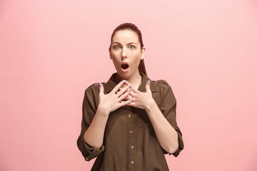 Wow. Beautiful female half-length front portrait isolated on pink studio backgroud. Young emotional surprised woman standing with open mouth. Human emotions, facial expression concept. Trendy colors