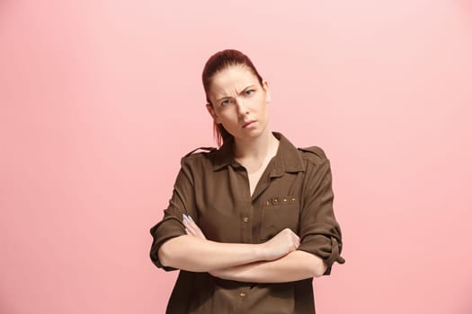 Serious business woman standing, looking at camera isolated on trendy pink studio background. Beautiful, young face. Female half-length portrait. Human emotions, facial expression concept. Front