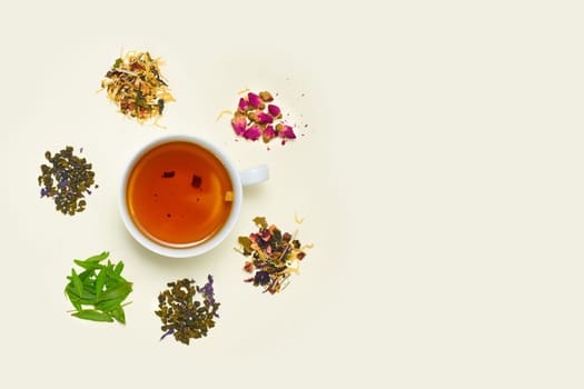 Cup of tea, placer of dry fruit tea and dry flowers on white background, top view