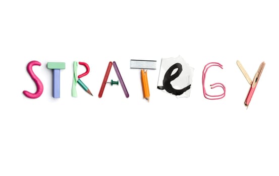 Concept of idea with colorful crumpled paper. The word strategy created from office stationery. The art, creative, letters concepts. Conceptual image. Top view, isolated on white desk. Work tool concept
