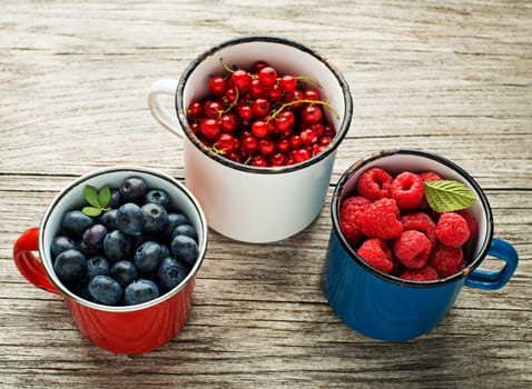 Mix of fresh berries in a bowls on wooden background
