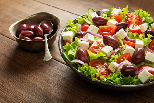 Salad with feta cheese and fresh vegetables on wooden background. Greek salad.