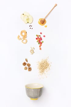 Falling granola with falling blueberries and honey flows from dipper. Healthy breakfast ingredients. Flying food