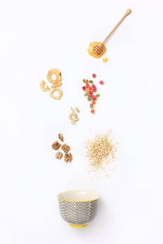 Falling granola with falling blueberries and honey flows from dipper. Healthy breakfast ingredients. Flying food