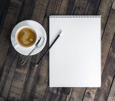 Blank notebook, coffee cup and pencil on vintage wooden background. Notepad and stationery. Flat lay.