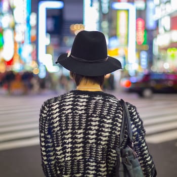 Solitary fashionably dressed young man waiting on crossroad in Kabukicho, entertainment and red-light district in Shinjuku, Tokyo, Japan.