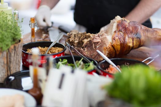 Cheff preparing traditional dish with cuts of pork ham meat on street stall on international street food festival of Odprta kuhna, Open kitchen event, in Ljubljana, Slovenia.