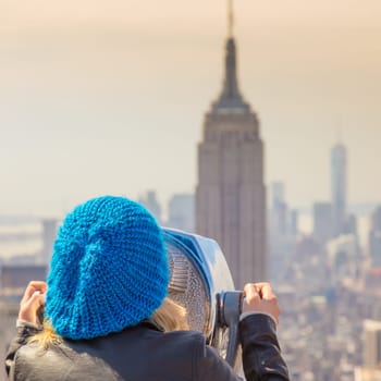 Woman enjoying in New York City panoramic view. Manhattan downtown skyline with illuminated Empire State Building and skyscrapers seen from observation deck terrace.