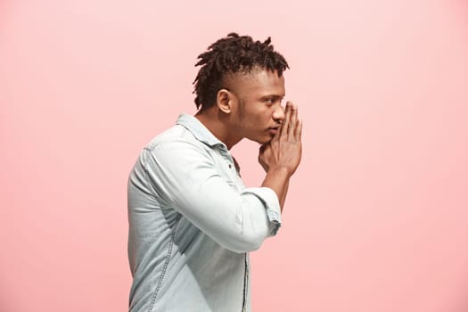 Secret, gossip concept. Young man whispering a secret behind his hand. Businessman isolated on trendy pink studio background. Young emotional man. Human emotions, facial expression concept. afro-american. profile