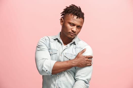 Pain concept. Beautiful afro male portrait isolated on pink backgroud. Young emotional surprised man looking at camera.Human emotions, facial expression concept. man overwhelmed with pain in shoulder