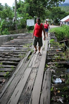 Tourists cross a creek on a dilapidated wooden bridge,Pintuyan,Panaon Island,Southern Leyte,Philippines