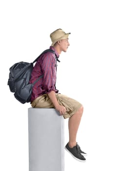 Side view of asian backpacker man with hat sitting isolated over white background
