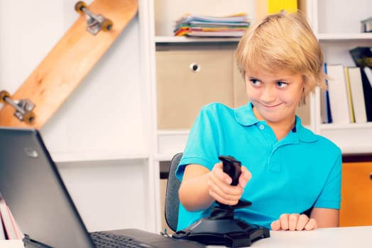 blond boy is playing computer game in his room