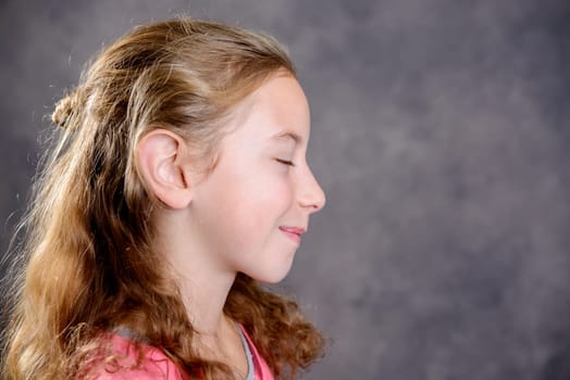 nice girl with blond hair and pink shirt in front of gray background