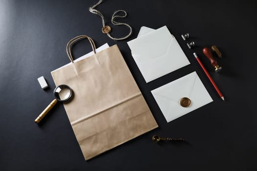 Blank vintage stationery with craft paper bag and mail envelopes on black paper background.