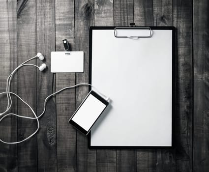 Corporate stationery mockup. Clipboard, blank letterhead, smartphone, badge and headphones on wood table background. Flat lay.