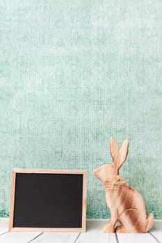 Traditional wooden Easter holiday bunny and an empty blackboard
