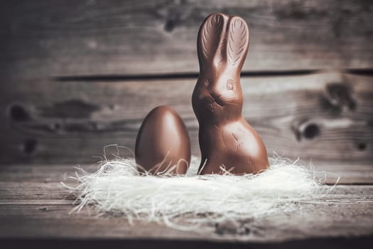 Delicious chocolate Easter bunny and egg on wooden background