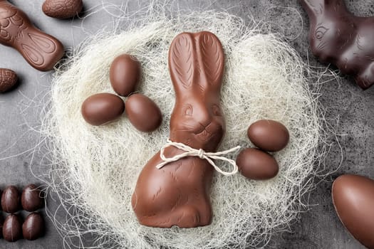 Delicious chocolate Easter bunny and eggs in a nest on rustic background
