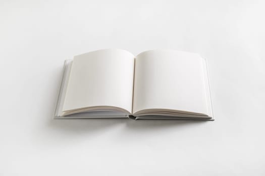 Opened blank book on white paper background.