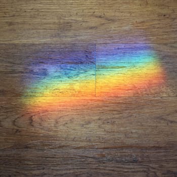 color prism projected onto a wooden floor. Refraction and science concept