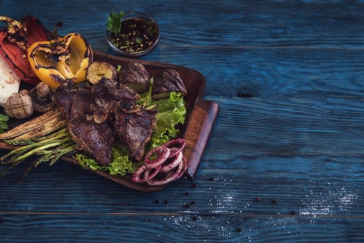 Grilled beef meat with vegetable on a blue wooden background