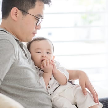 Asian family at home. Father holding baby boy, living lifestyle indoors.