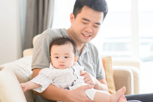 Asian family at home. Father babysitting son, living lifestyle indoors.