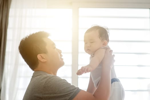 Happy Asian family at home. Father carrying his 9 months old baby boy, living lifestyle indoors.