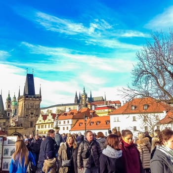 Prague, Czech Republic - December 31, 2017: People walking on the historic Charles Bridge that crosses the Vltava river overlooking its entrance tower.