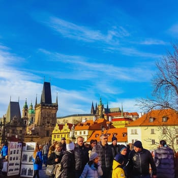 Prague, Czech Republic - December 31, 2017: People walking on the historic Charles Bridge that crosses the Vltava river overlooking its entrance tower.