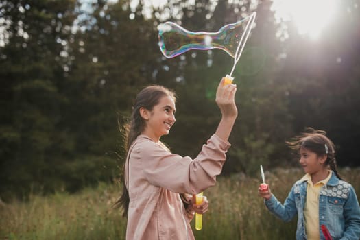 Two little girls creating bubbles in the woodlands on their holiday.