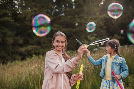 Two little girls creating bubbles in the woodlands on their holiday.