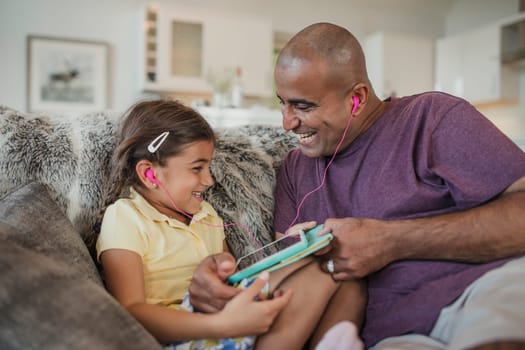 Father and daughter laughing together, using a digital touch screen tablet.