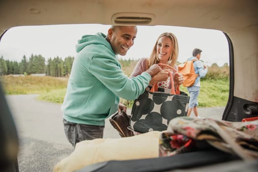 Husband and wife unpacking the car while having a laugh.