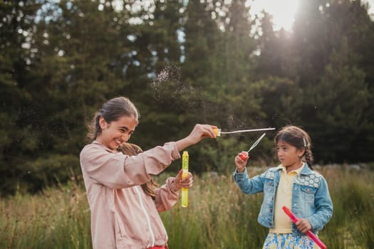 Two little girls creating bubbles in the woodlands on their holiday.