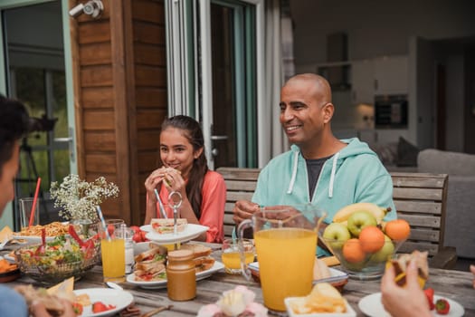 Family having brunch outside, eating a sandwich.