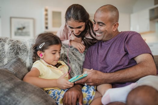 Father and his two daughters using and looking at the digital tablet and laughing.
