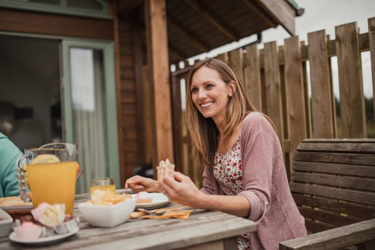 Female looking at someone out of frame, having a discussion while sitting down outside at breakfast.