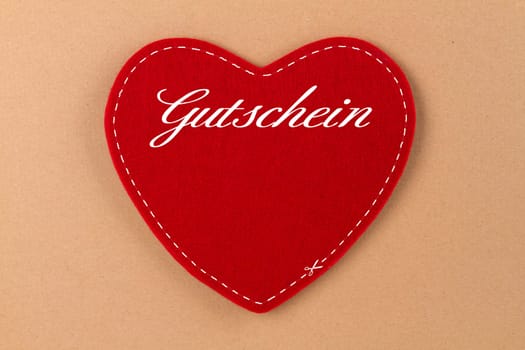 Heart made of felt with inscription voucher on brown background