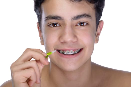 Cute teenager with white background, wearing braces on his teeth. Use a small toothbrush.