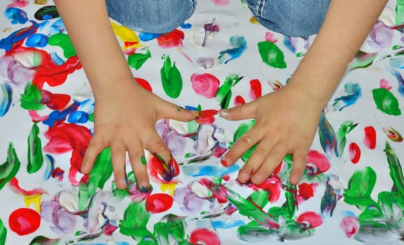 Kid paints with her fingers with different color paint