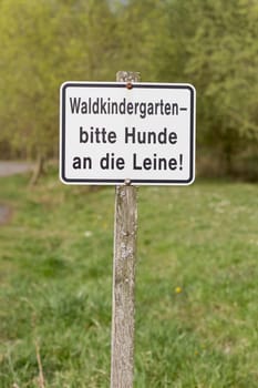 german sign on wooden pole. forest kindergarten,dogs please on the leash
