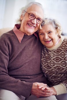 Cheerful senior couple in sweaters looking at camera