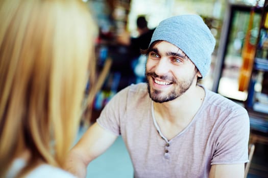 Young guy looking at his girlfriend while listening to her